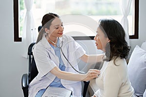 Portrait of a female doctor using a stethoscope to check the pulse of an elderly patient.