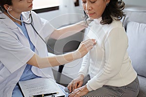 Portrait of a female doctor using a stethoscope to check the pulse of an elderly patient.