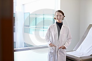 Portrait Of Female Doctor Wearing White Coat In Exam Room