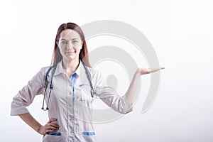 Portrait of a female doctor in a white uniform that shows a palm with copyspace in the studio on a white background.