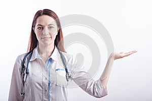 Portrait of a female doctor in a white uniform that shows a palm with copyspace in the studio on a white background.