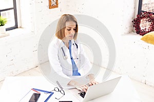 Portrait of female doctor working on laptop in doctor`s office