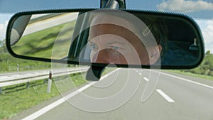 Portrait of female driver in car rear view mirror