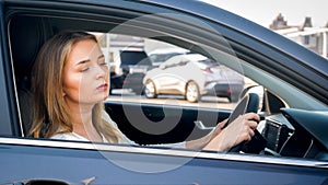 Portrait of female driver looking out of the open window while driving a car in city