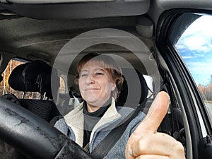 Portrait of female driver in solo journey. Adult mature woman holding steering wheel and looking through windscreen in