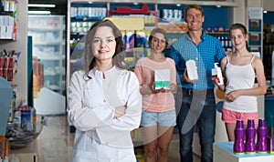 Portrait of female druggist in white coat working in pharmacy
