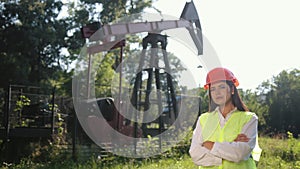 Portrait of female engineer against background of oil drilling rig. Put hands