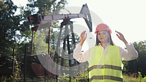 Portrait of female engineer against background of oil drilling rig. Put hands