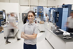 Portrait Of Female Engineer On Factory Floor Of Busy Workshop