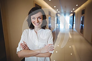 Portrait of female executive standing with arms crossed in corridor