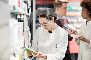 Portrait of a female experienced pharmacist reading indications photo