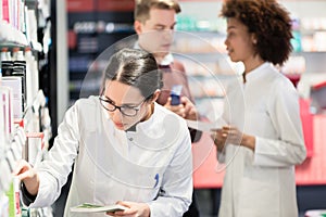 Portrait of a female experienced pharmacist reading package indications photo