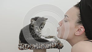 portrait female face kissing little kitten gray striped cat pet owner lips nose