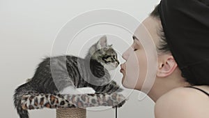 portrait female face kissing little kitten gray striped cat pet owner lips nose