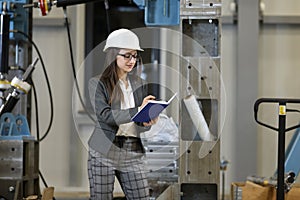 Portrait of a female factory manager in a business suit holding notebook, controlling the work process in the manufacture