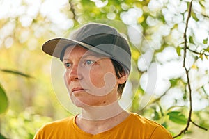 Portrait of female farm worker wearing orange t-shirt and trucker`s hat in walnut tree orchard