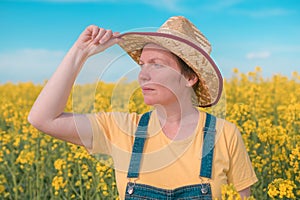Portrait of female farmer agronomist in blooming rapeseed crops field
