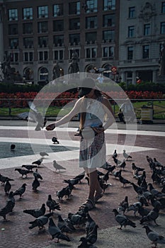 Portrait of a female feeding a flock of pigeons in a park