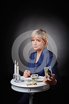 Portrait of a female fortune teller with tarot cards, on a black background