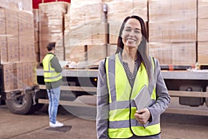 Portrait Of Female Freight Haulage Manager Standing By Truck Being Loaded By Fork Lift  photo