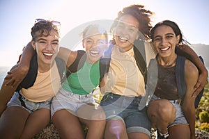 Portrait Of Female Friends With Backpacks On Vacation Taking A Break On Hike Through Countryside