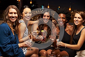 Portrait Of Female Friends Enjoying Night Out At Rooftop Bar