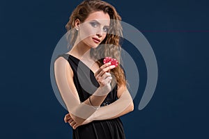 Portrait of the female gambler at the casino keeping poker chips in the hand