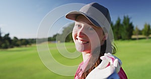 Portrait of female golf player smiling with gold club on her back on golf course