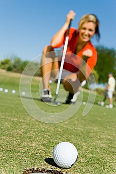 Portrait of Female Golfer Watching Putt Sink