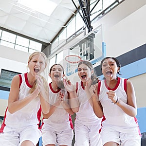 Portrait Of Female High School Basketball Team Celebrating On Court