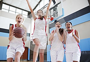 Portrait Of Female High School Basketball Team Celebrating On Court