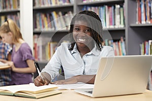 Portrait Of Female High School Student Working At Laptop In Library