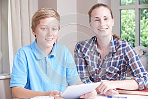 Portrait Of Female Home Tutor Helping Boy With Studies Using Dig photo