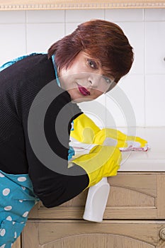 Portrait of female houseworker dusting kitchen