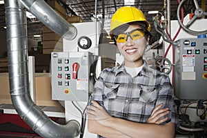 Portrait of female industrial worker smiling while standing in factory with machines in background photo