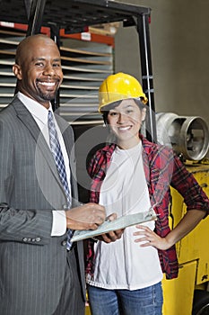 Portrait of female industrial worker standing with male inspector