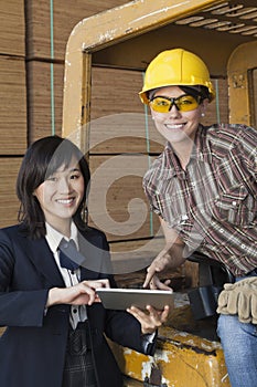 Portrait of female inspector and industrial worker using tablet PC