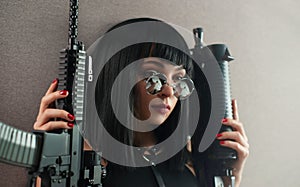 portrait of a female killer with an automatic rifle in round glasses