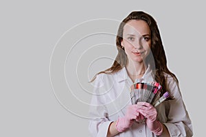 Portrait of a female manicurist with accessories on a gray background