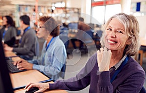 Portrait Of Female Mature Adult Student In Class Working At Computers In College Library