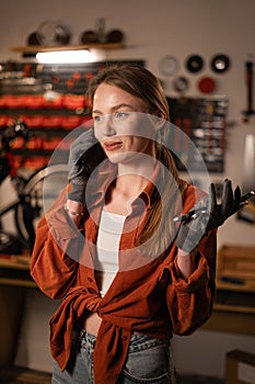 Portrait of a female mechanic talking on a cell phone while standing in a workshop or old garage. Bicycle maintenance