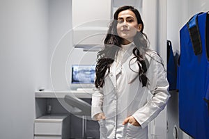 Portrait of female medic in CT scan room. Woman near the tomograph.