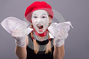 Portrait of female mime angry crumpling a paper