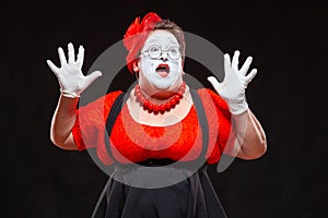 Portrait of female mime artist, isolated on black background. Racy woman throwing up her hands and shouting. Symbol of