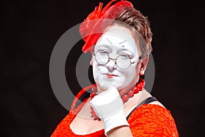 Portrait of female mime artist, isolated on black background. Racy woman touches her chin with a finger looking languid