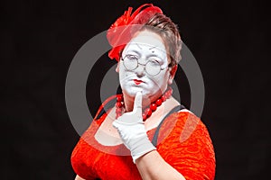 Portrait of female mime artist, isolated on black background. Racy woman touches her chin with a finger looking languid photo
