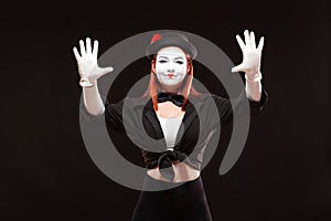 Portrait of female mime artist performing, isolated on black background. Woman is gesticulating with her hands looking photo