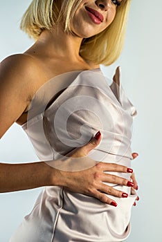 Portrait of a female model of a blonde girl in a beautiful evening silk dress in the studio.