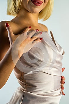 Portrait of a female model of a blonde girl in a beautiful evening silk dress in the studio.