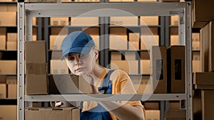 Portrait of female model working in storage. Girl storekeeper standing near rack with boxes, drinking coffee taking